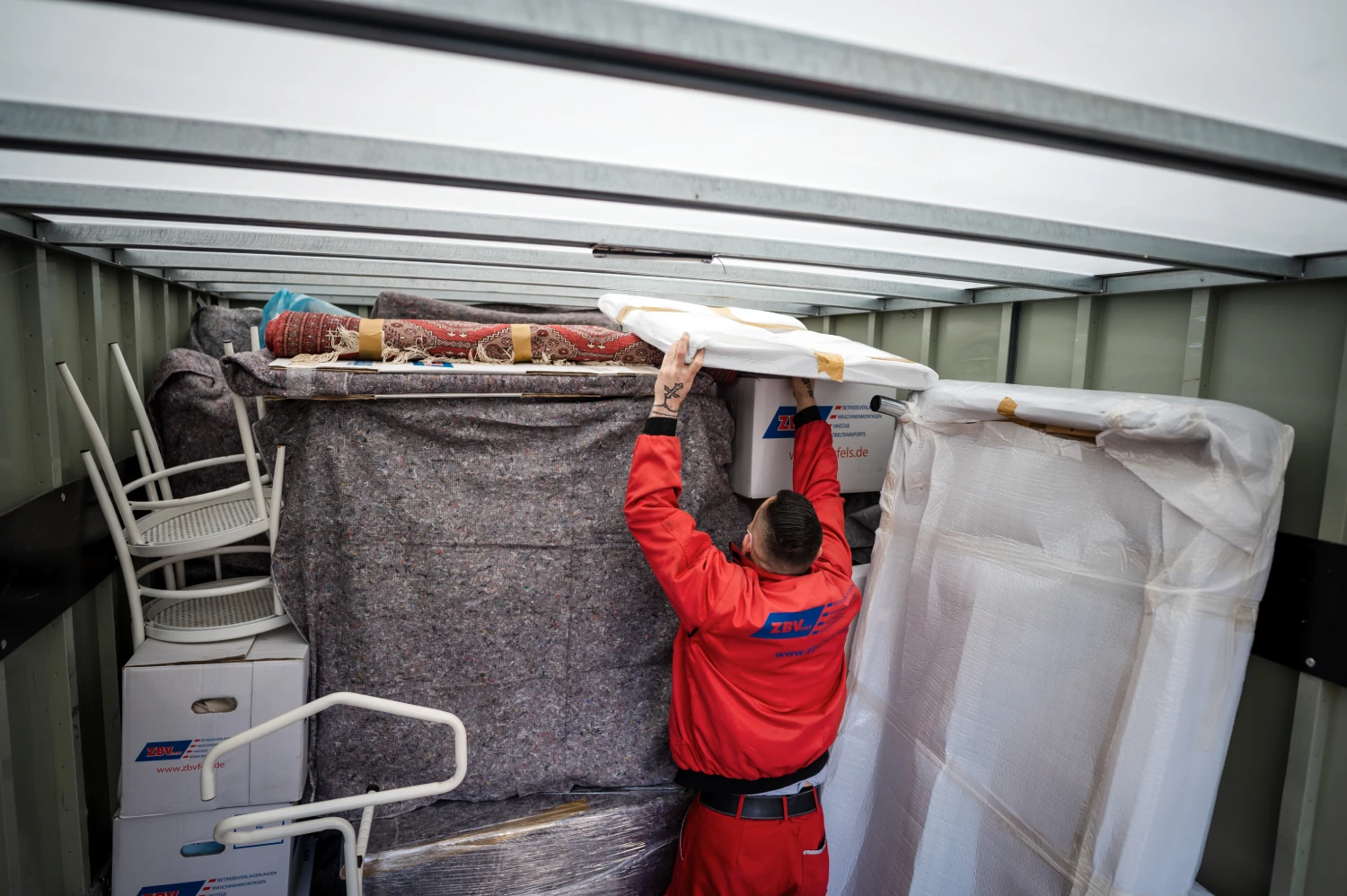 Ein Mitarbeiter von ZBV Fels verstaut Möbel und Haushaltsgegenstände in einem Lagercontainer.