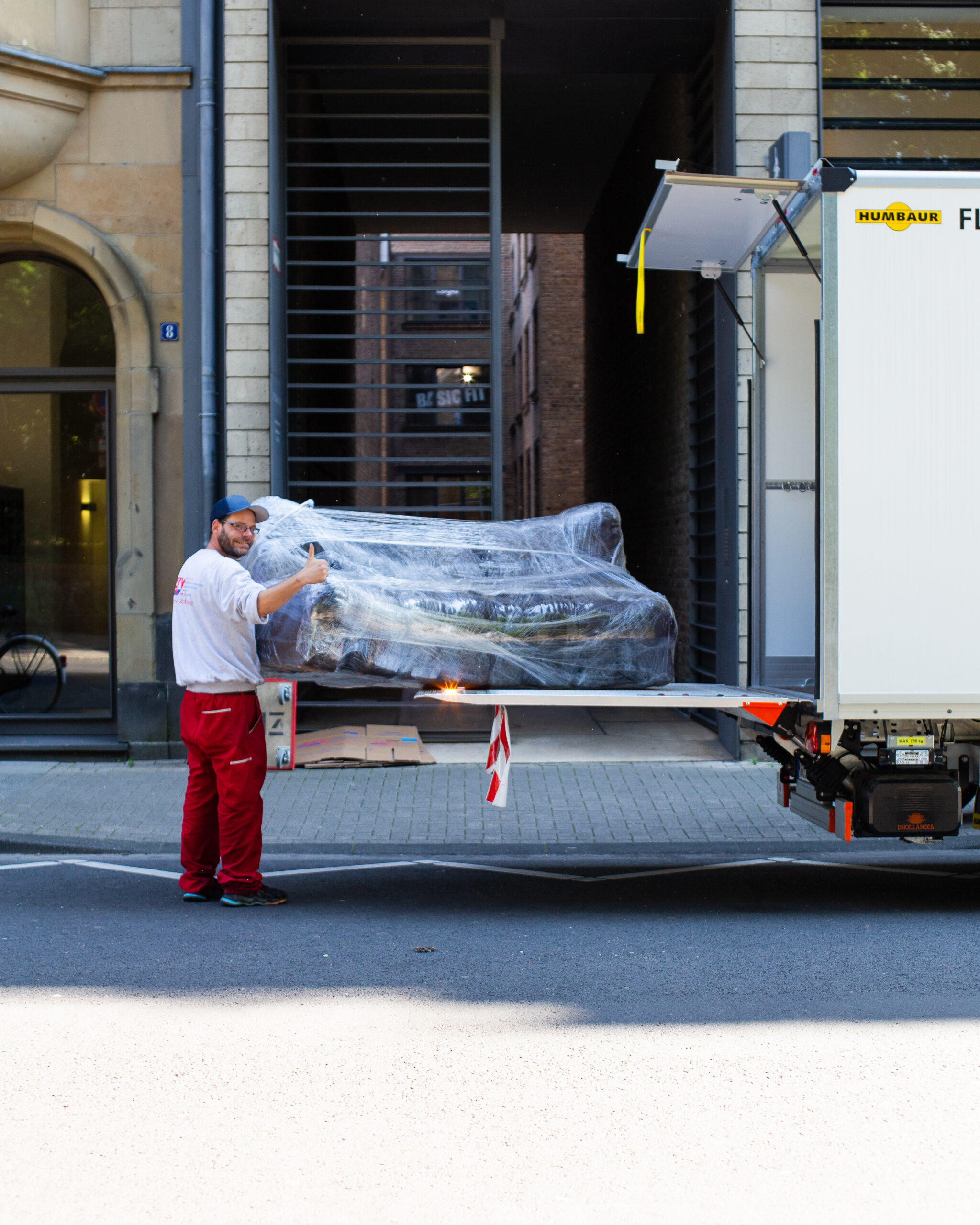 Ein Mitarbeiter von ZBV Fels hält ein verpacktes Sofa auf der Laderampe eines Lkw.