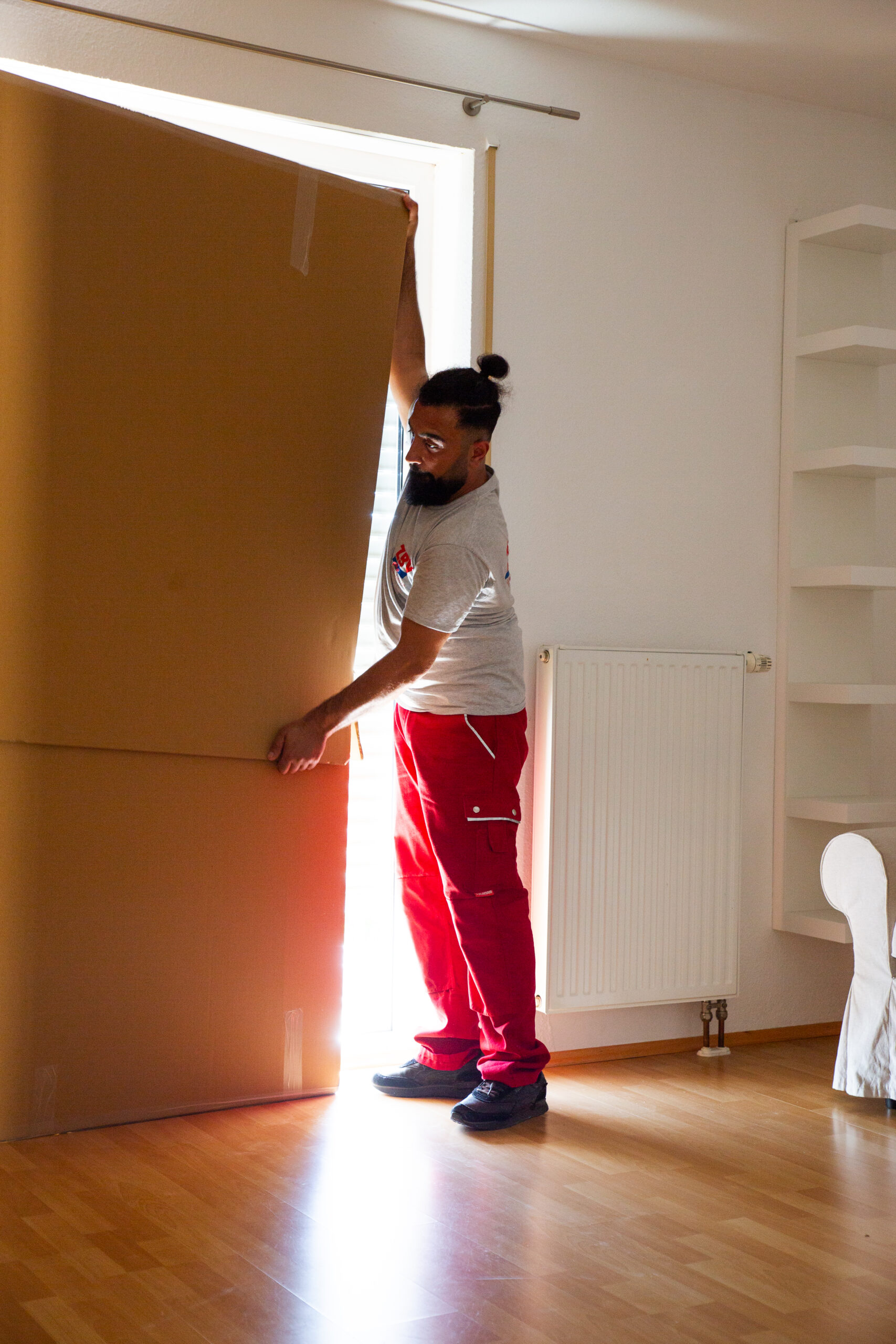 Ein Mitarbeiter von ZBV Fels trägt einen großen Karton in einen hellen Raum.