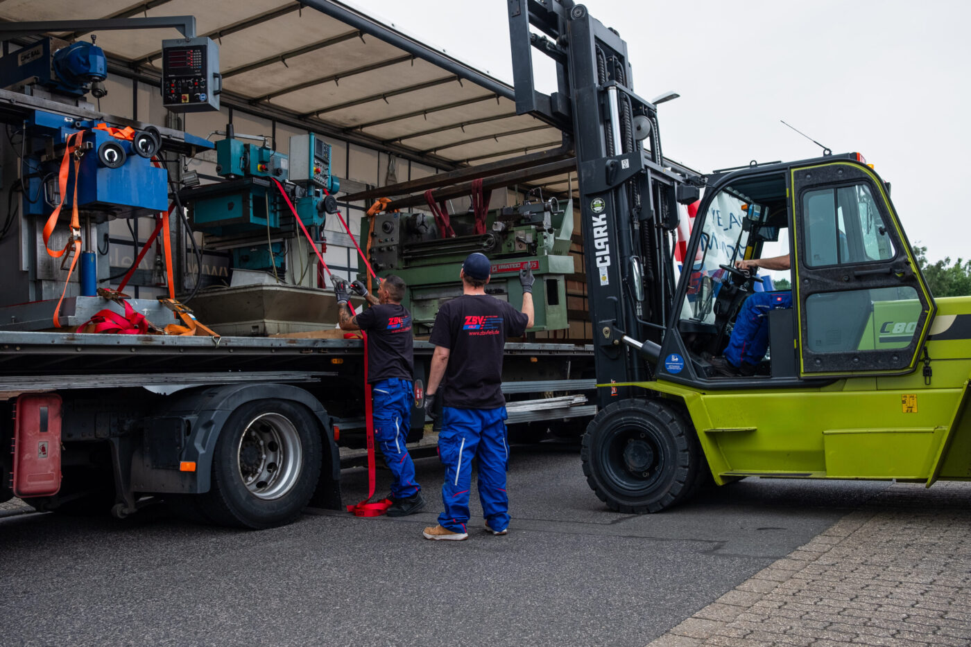 Das Team von ZBV Fels lädt Maschinen mit dem Gabelstapler in einen Lkw und sichert sie mit Spanngurten.