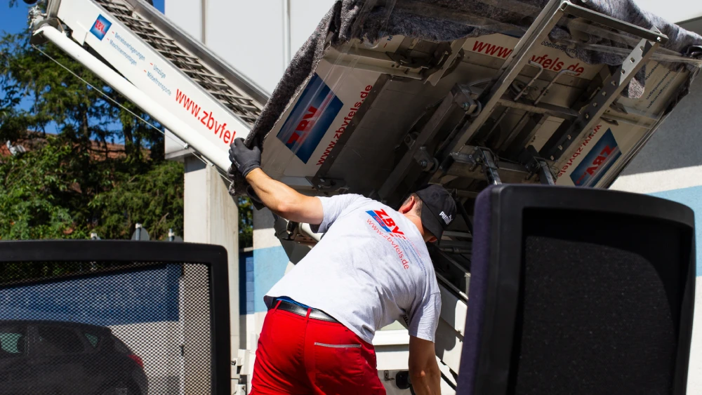 Ein Mann kippt einen Container auf die Ladefläche eines Lkw.